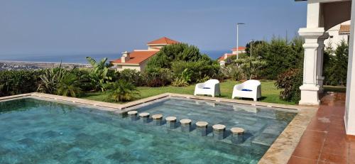 une piscine avec deux chaises et une maison dans l'établissement villa star hill Tanger, à Tanger