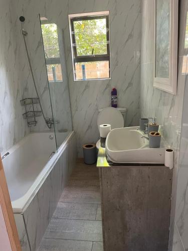 a bathroom with a tub and a toilet and a sink at Thabi's Place in Matatiele