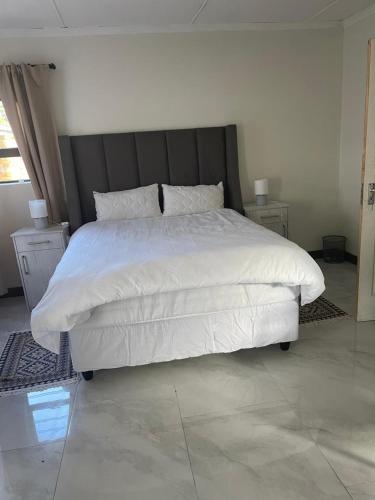 a bedroom with a white bed with a black headboard at Thabi's Place in Matatiele