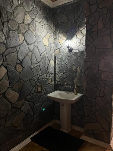 a bathroom with a sink and a stone wall at Sheki Modern Guest Home in Sheki