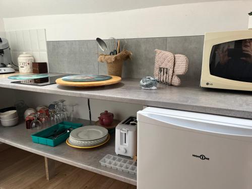 a kitchen counter with a microwave on a shelf at L'Herbe de grâce in Plachy-Buyon