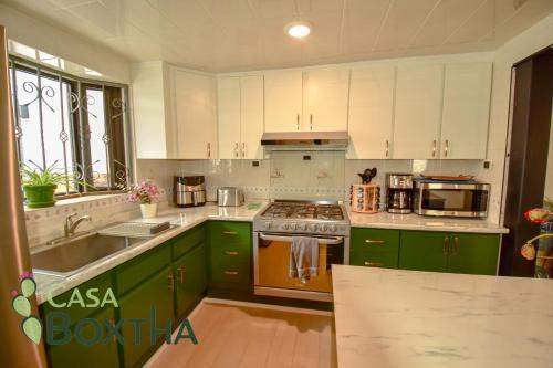 a kitchen with green cabinets and a stove top oven at Casa Boxtha in Ixmiquilpan
