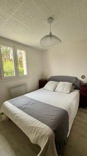 a bedroom with a large white bed with a ceiling at Villa Bleu soleil in Pornic