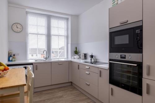a kitchen with white cabinets and a sink and a microwave at Antonine Quarters in Grahamston