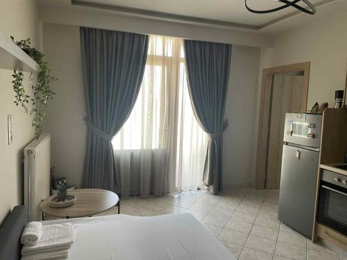 a bedroom with blue curtains and a table and a refrigerator at La casa de verano in Skala Sotiros