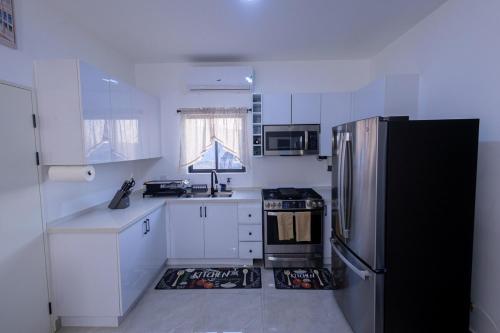 a kitchen with white cabinets and a black refrigerator at Sunset Sea-renity Villa in Belle Air Summit