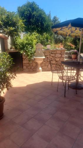 a patio with a table and chairs and a stone wall at Casa del Sole in Capo dʼOrlando