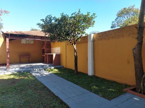 a backyard with a yellow wall and a tree at Encarnacion House in Encarnación
