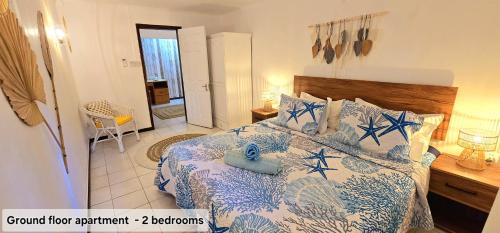 a bedroom with a bed with blue and white sheets at LAKAZ DEL SOL - Modern and elegant apartments with luxurious garden, pool and barbecue area - Tourism Permit Certified in Tamarin