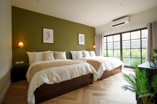 2 Betten in einem Schlafzimmer mit grünen Wänden in der Unterkunft Hestiana in Ban Hua Khao Sammuk