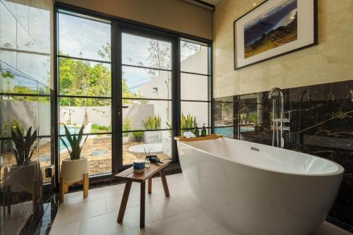 ein Badezimmer mit großer Badewanne und großem Fenster in der Unterkunft Hestiana in Ban Hua Khao Sammuk