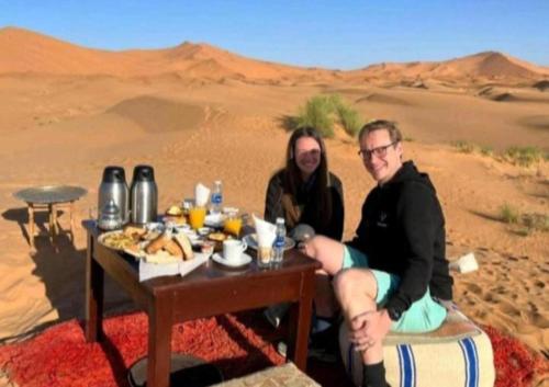 twee mensen aan een tafel in de woestijn bij Luxury Sahara Gold Camp in Merzouga