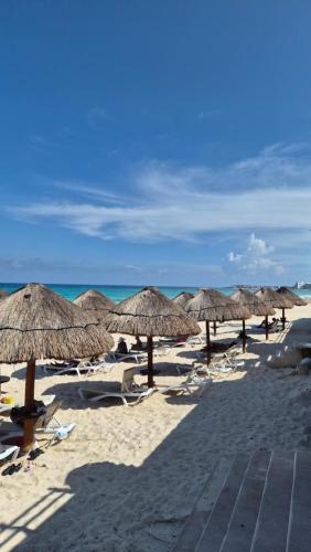 a group of straw umbrellas on a beach at Front Beach Studio in Cancún