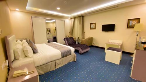 a hotel room with a large bed and a chair at Al Maali Hotel Jazan in Jazan