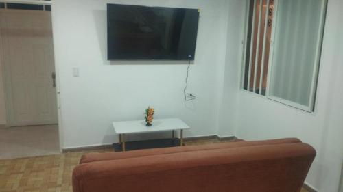 a living room with a couch and a tv on a wall at Hospedarte Cali Sur in Cali