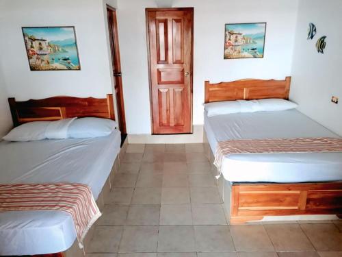 two beds in a room with a door at Villas Caracol in Las Tablas
