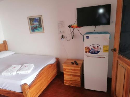 a small bedroom with a refrigerator and a tv on the wall at Villas Caracol in Las Tablas