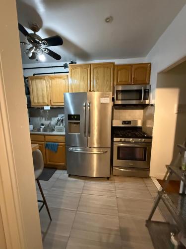 a kitchen with stainless steel appliances and wooden cabinets at Bronx City Stay Private Room Near Manhattan in Kings Bridge Heights