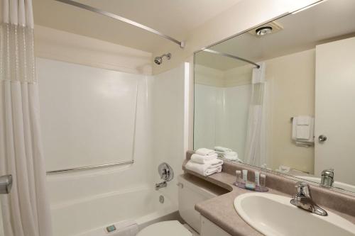 a bathroom with a sink and a toilet and a mirror at Travelodge by Wyndham Nanaimo in Nanaimo