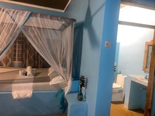 a bedroom with a canopy bed in a blue room at AfroWhaleSharkSafari & AfroBeachBungalows in Kilindoni