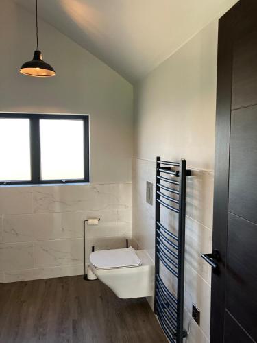 a white bathroom with a toilet and a window at Stunning Contemporary Dutch Barn Conversion in Whixall