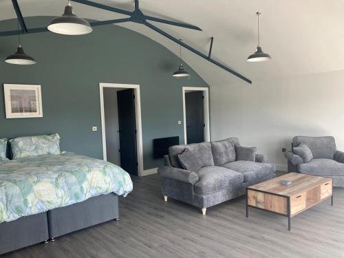 a bedroom with a bed and a couch and a table at Stunning Contemporary Dutch Barn Conversion in Whixall