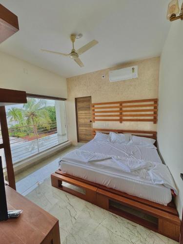 a bedroom with a bed and a desk and a window at Grove Stay in Chakkarakkal