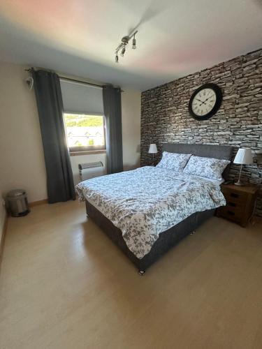 a bedroom with a bed and a clock on a brick wall at No 52 - Apartment with Lounge and Dining Area - No kitchen in Ullapool