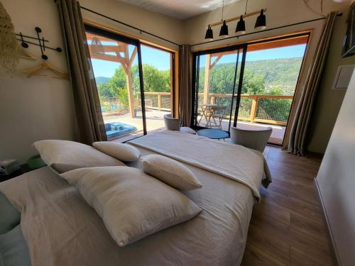 - une chambre dotée d'un lit avec des oreillers et d'une grande fenêtre dans l'établissement Chalet, hot tub and pool, quiet and with a view Sawadee lodge spa, à Saint-Affrique