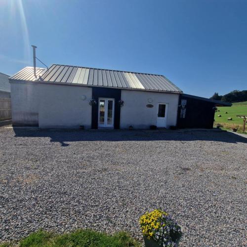 a small white building with a gravel driveway at Pleasant Point Holiday Cottages in Glenurguhart