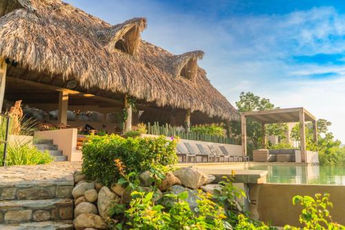 a resort with a thatched roof and a pool at Casa Las Almas in Mazunte