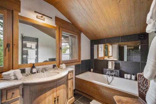 une salle de bain avec une baignoire et un lavabo dans l'établissement Prestigious 7BR Alpine Chalet - Sauna, Home Cinema & Mont Blanc Panorama, à Megève