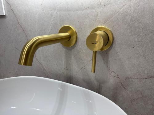 a bathroom with a toilet with a gold faucet at CASHMERE Apartment - Airport Katowice-Pyrzowice in Siewierz