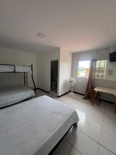 a bedroom with two beds and a window and a desk at Hotel MELAO in Pedernales