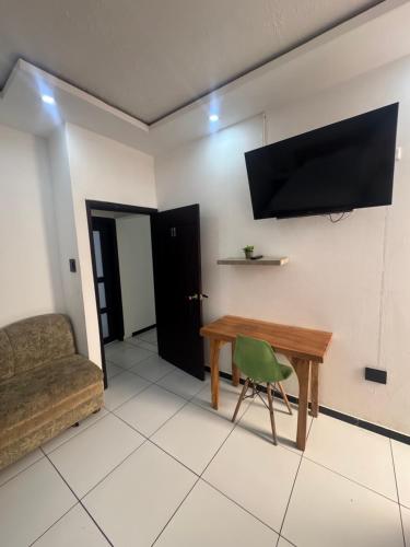 a living room with a table and a chair and a television at Hotel MELAO in Pedernales
