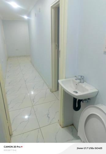 a white bathroom with a sink and a toilet at Raneziah Guesthouse in Kasane