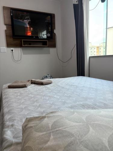 een slaapkamer met een bed en een tv aan de muur bij Apartamento mobiliado com piscina in Ananindeua