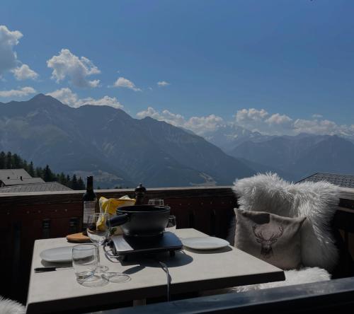 a table with a pot and glasses on a balcony with mountains at Chalet La Montanara in Bettmeralp