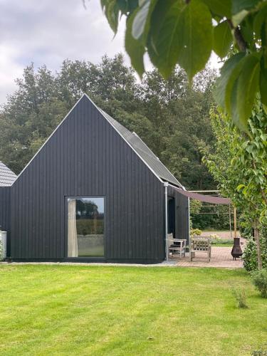 a black house with a large window on the side of it at Tiny house Steygheren in Stegeren