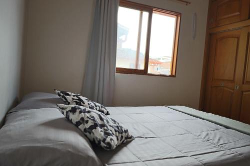a bed with two pillows in a bedroom with a window at Apartamento amoblado en Guatape in Guatapé