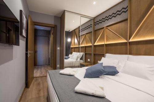 a bedroom with a bed with white sheets and blue pillows at Zlatibor Lux Spa Apartments in Zlatibor