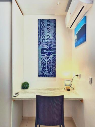 a table with a chair and a picture on the wall at Charmant logement avec accès privé à la plage in Moorea