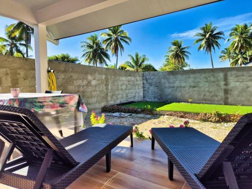 a patio with chairs and a table and a fence at Charmant logement avec accès privé à la plage in Moorea