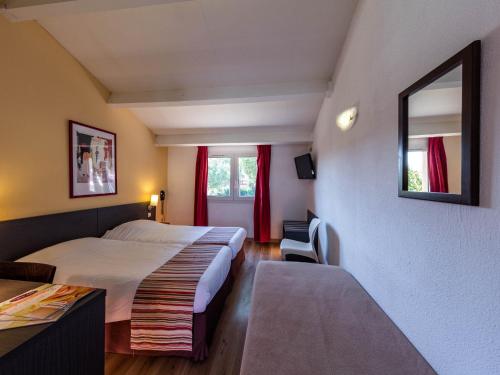 Habitación de hotel con cama y ventana en Noemys Aigues-Mortes - Hotel avec piscine, en Aigues-Mortes