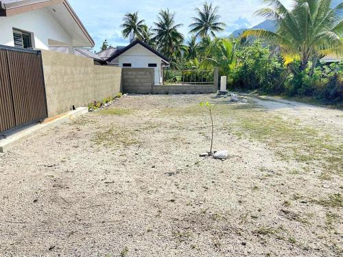 a yard in front of a house with a fence at Charmant logement avec accès privé à la plage in Moorea