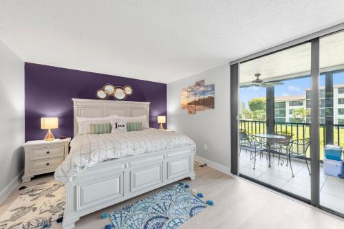 a bedroom with a white bed and a balcony at Steps To The Beach Loggerhead 472 in Sanibel