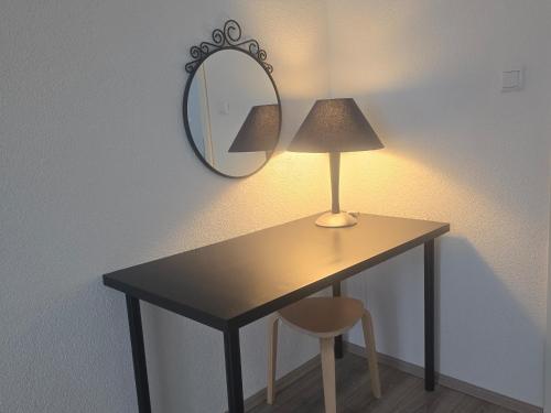 a table with a lamp and a mirror on a wall at Apartment Flora three in Duisburg