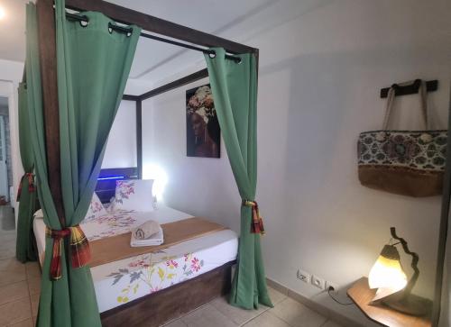 a bedroom with a bed with green curtains at Mi Plézi Appartement au Diamant. in Le Diamant