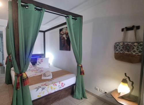 a bedroom with a bed with green curtains at Mi Plézi Appartement au Diamant. in Le Diamant