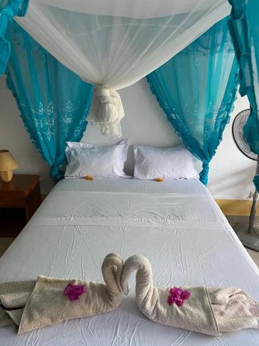 a bed with two swans towels on it at Studio Cannelle - À deux pas de la plage Nosy Be in Nosy Be